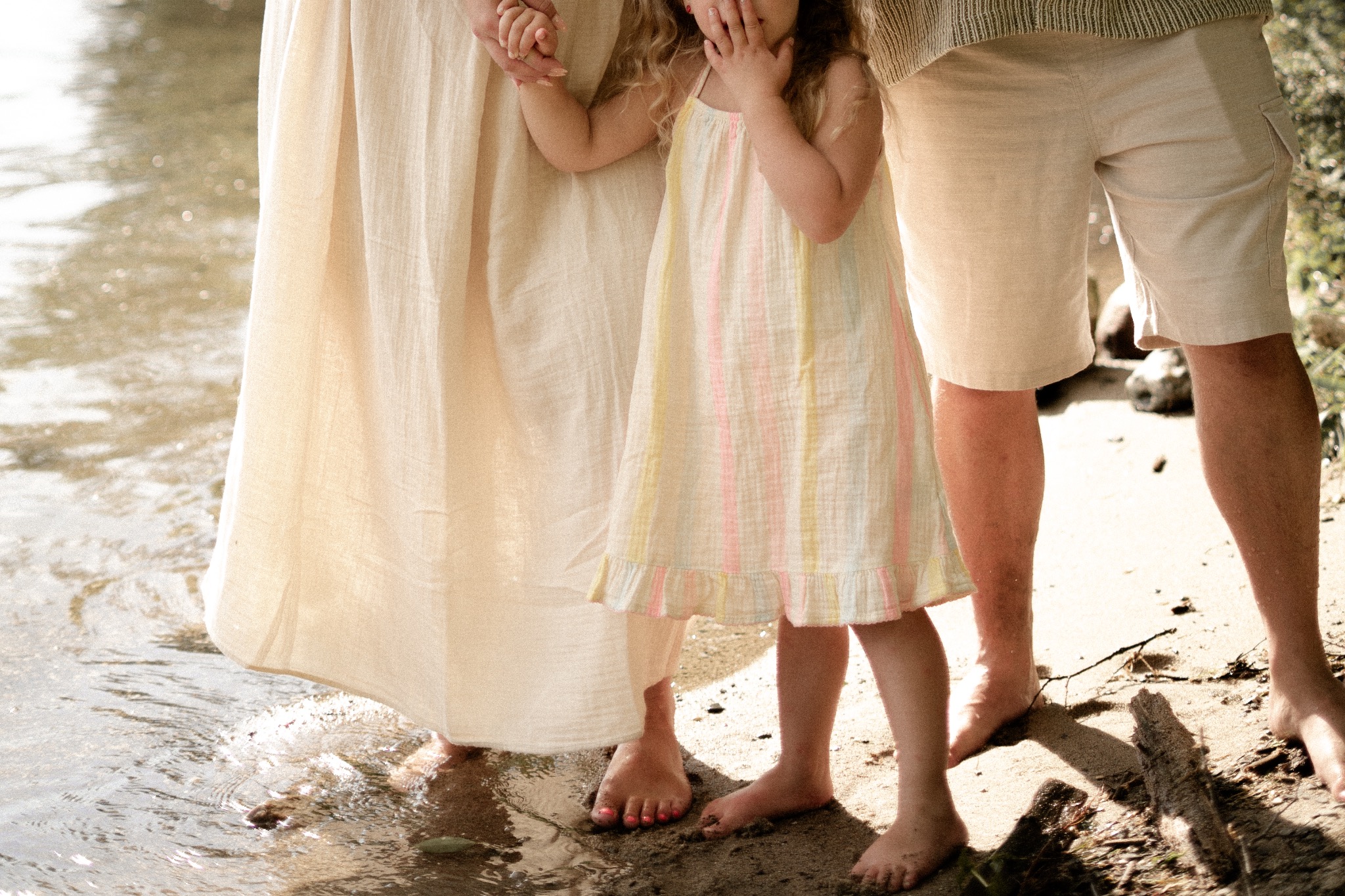 A child holding both parents' hands beside the water