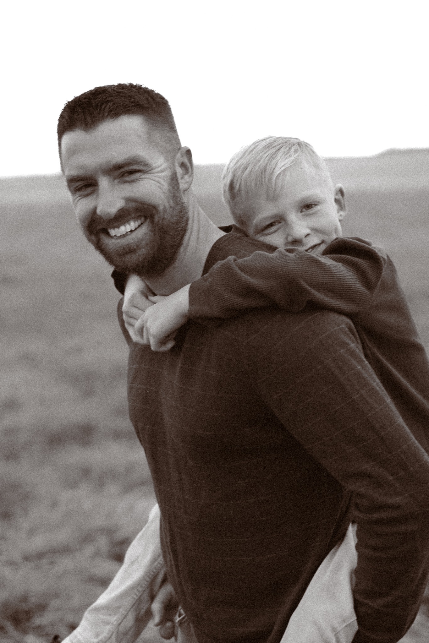 A smiling father giving his son a piggyback ride