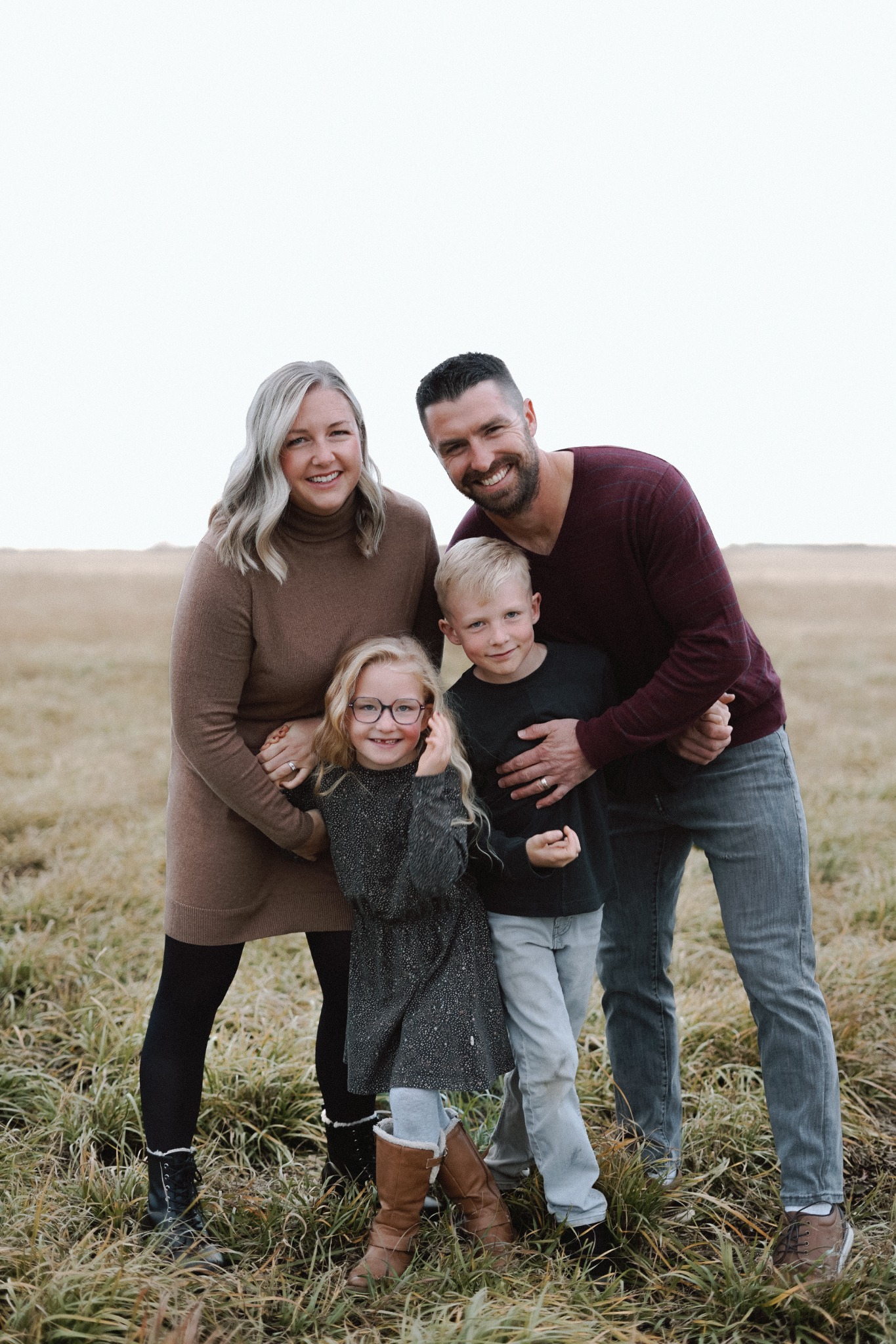 A family of four standing together in a prairie field
