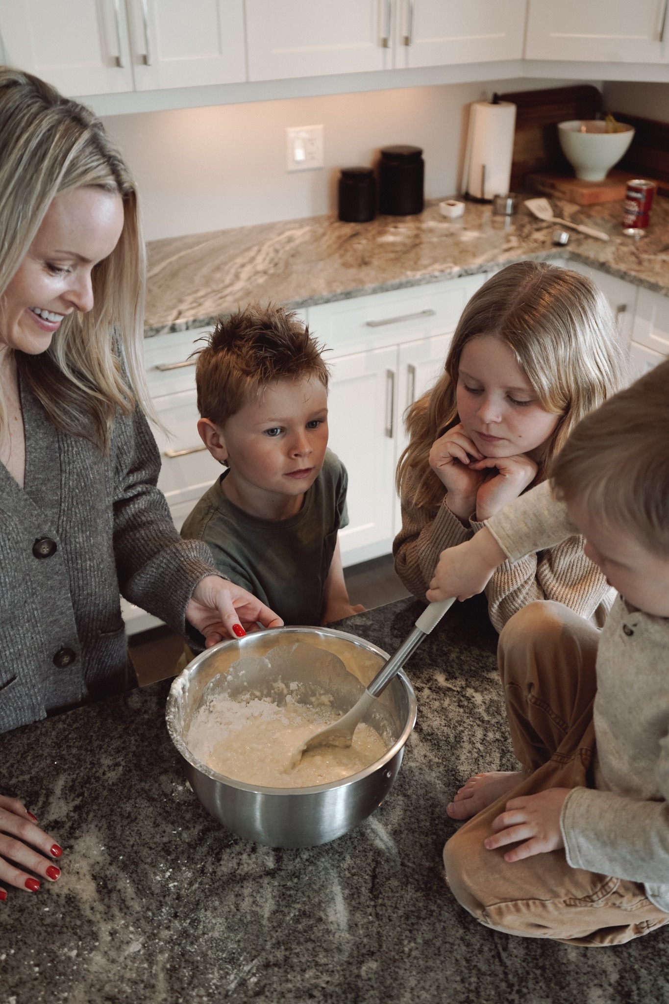 A mother and three children gathered around a mixing bowl
