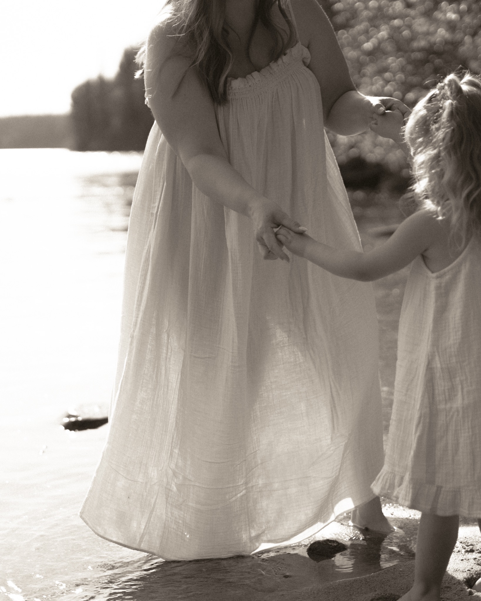 A mother and daughter holding hands in shallow water